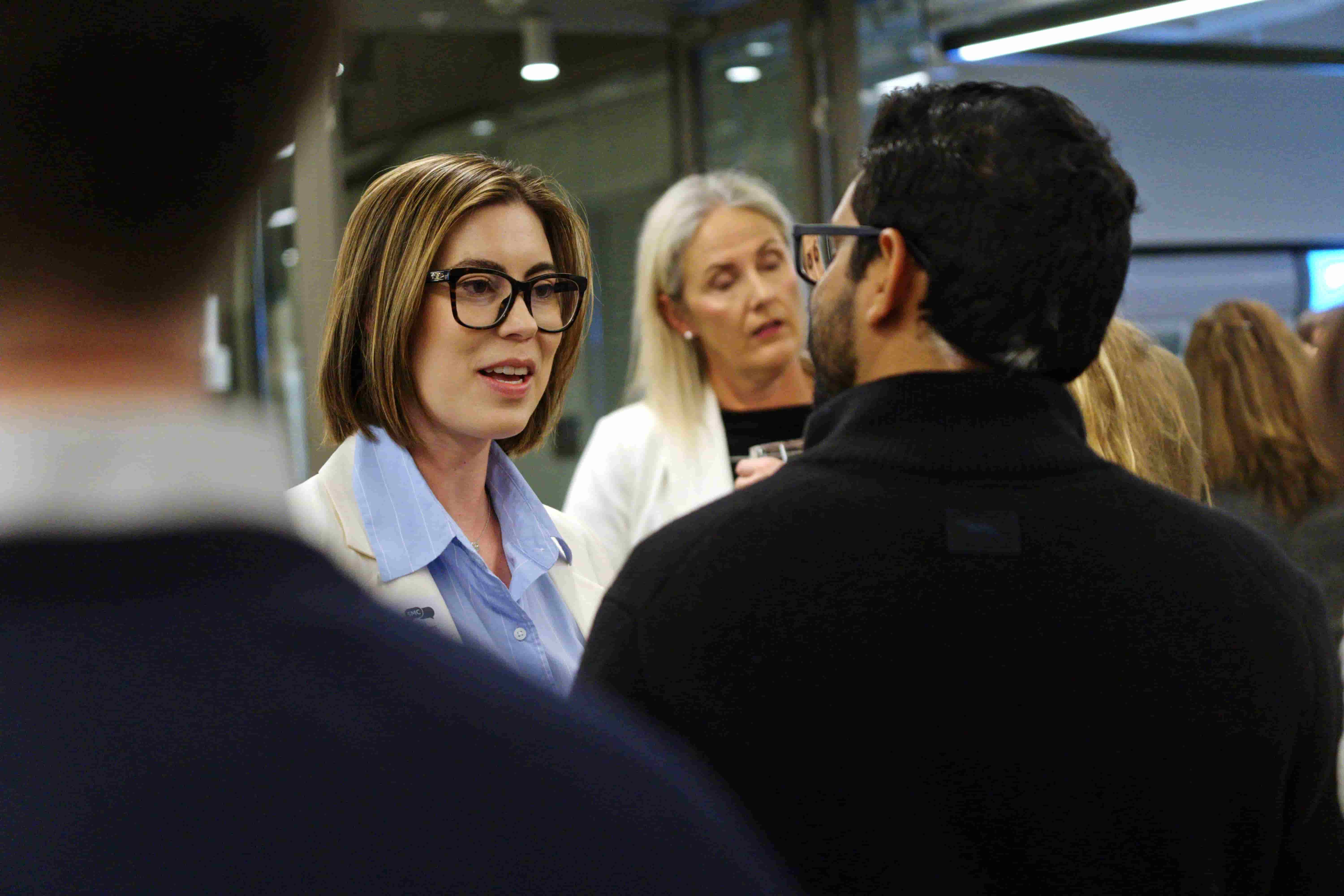 Several people talking in a group, one woman in the foreground